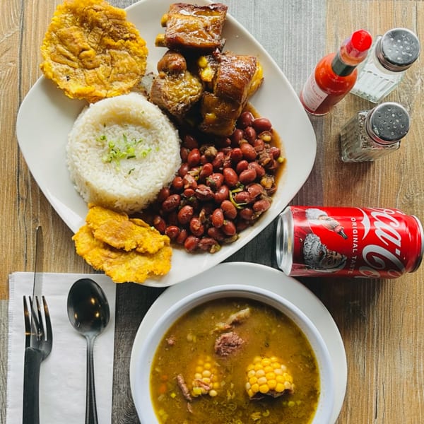 A Colombian meal with rice, beans, meat, plantains, soup, and a Coca-Cola.