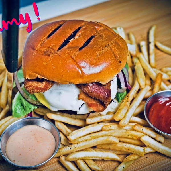 A Chapa Paisa burger with bacon, cheese, and lettuce, served with fries and two dipping sauces.