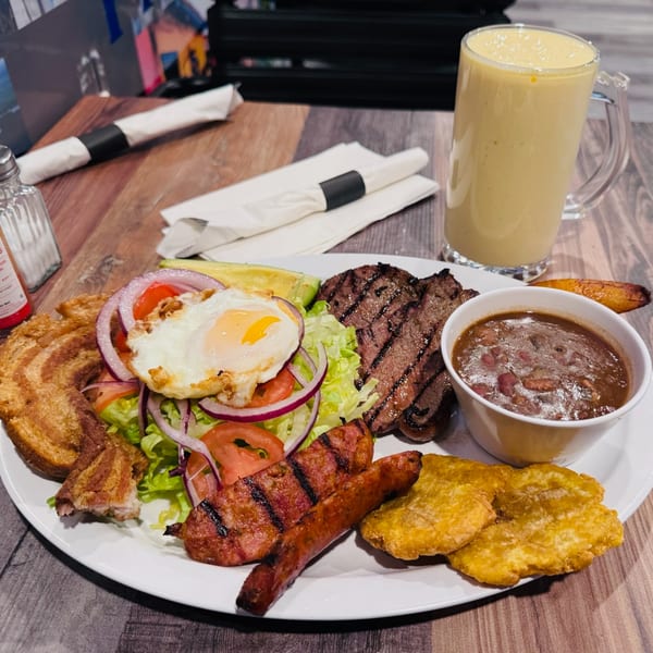 A Colombian bandeja paisa with steak, sausage, fried egg, beans, plantains, and chicharron.